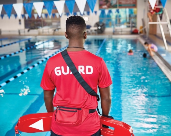 Participants in Lifeguard, AED, First Aid, and CPR certifications at the YMCA of Central Virginia. A man in a red shirt standing by the pool.