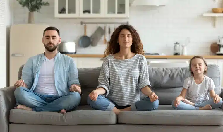 a man and woman meditating on a couch