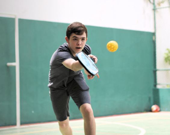 kid playing pickleball indoors