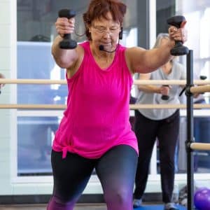 a woman in a pink tank top holding weights