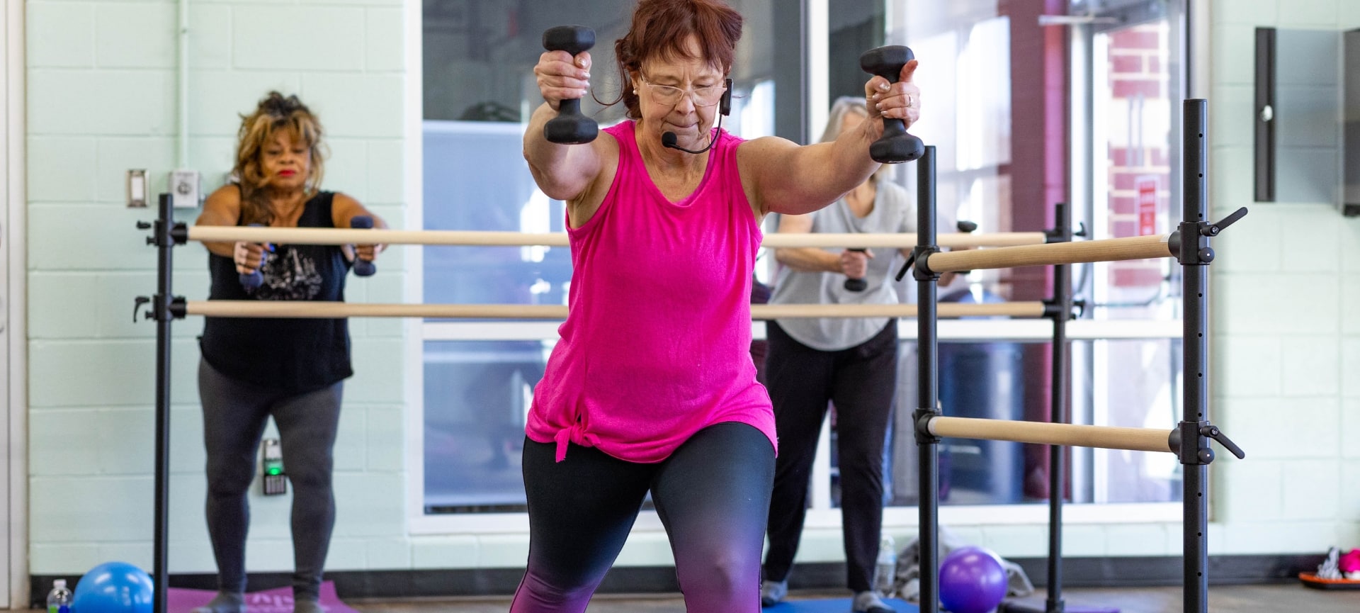 a woman in a pink tank top holding weights