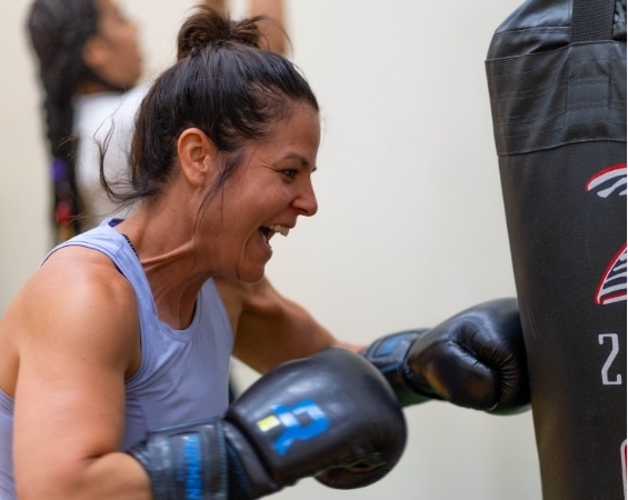 a woman punching a punching bag at better you bootcamp premier programs class at YMCA of the East Bay.