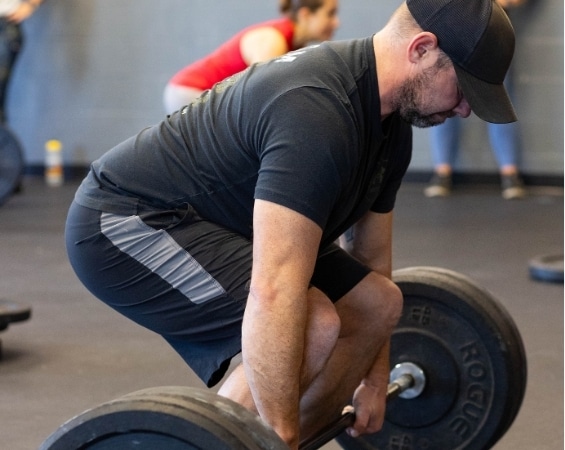 a man lifting a barbell at crossfit forged iron premier programs class at YMCA of the East Bay.