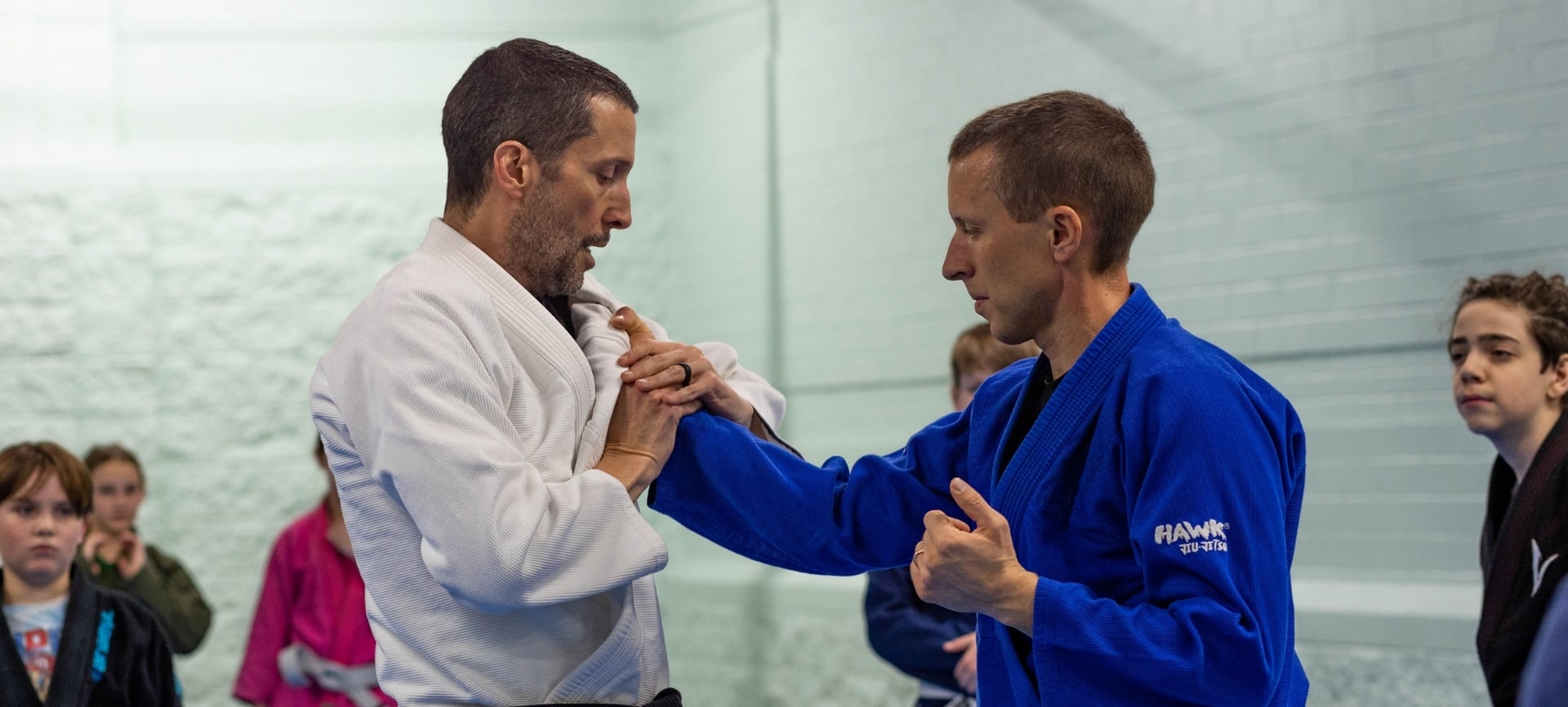a man in a white robe holding another man in a blue robe - Jiu-Jitsu