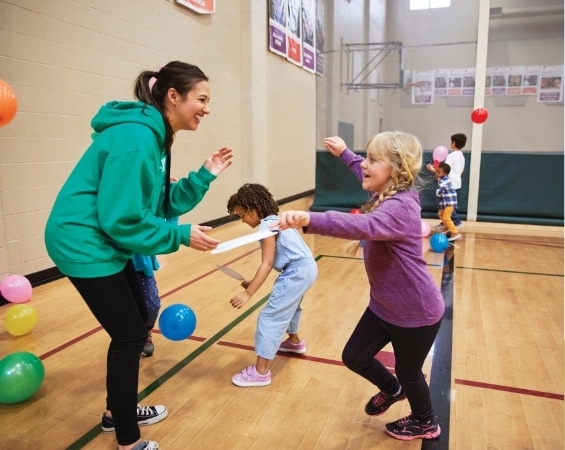 a woman and children playing in a gym
