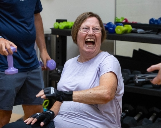 a woman laughing while holding weights