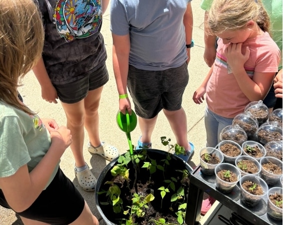 a group of kids planting a plant