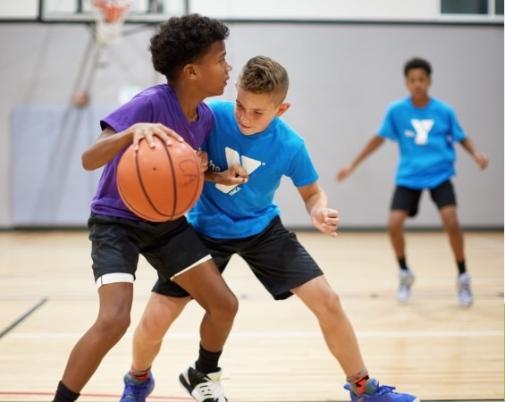 a young boys playing basketball in a gym