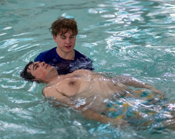a man swimming in a pool with another man