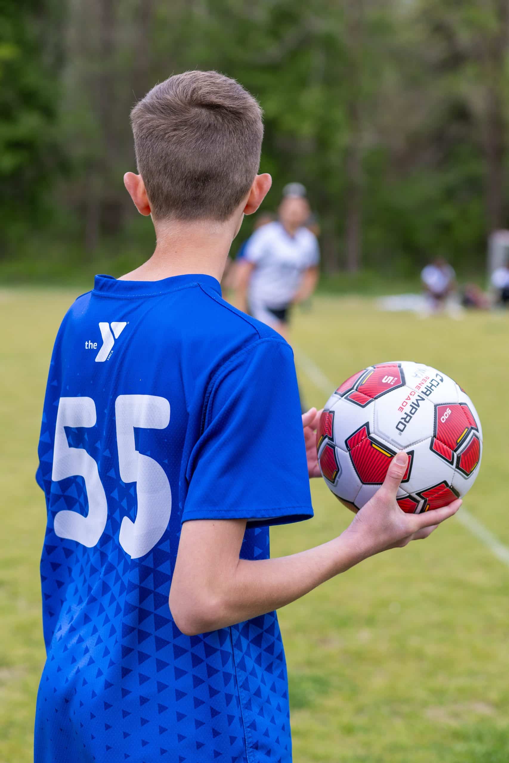 Boy in blue jersey holding soccer ball